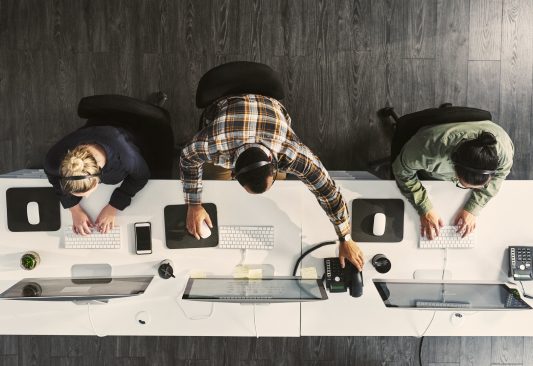Shot taken from above of three people working on computers